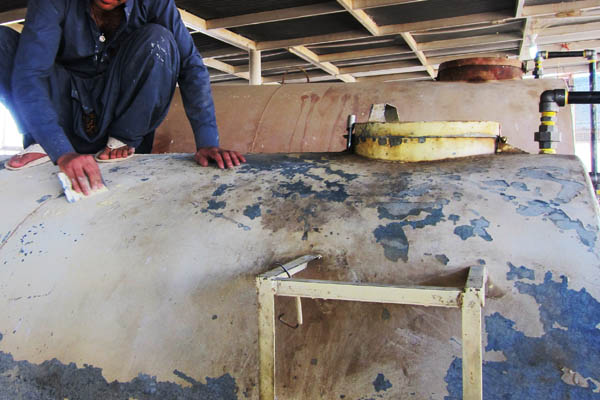 Scraping old paint off a diesel fuel storage tank